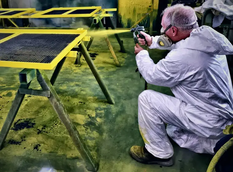 Peintre en combinaison appliquant une peinture jaune